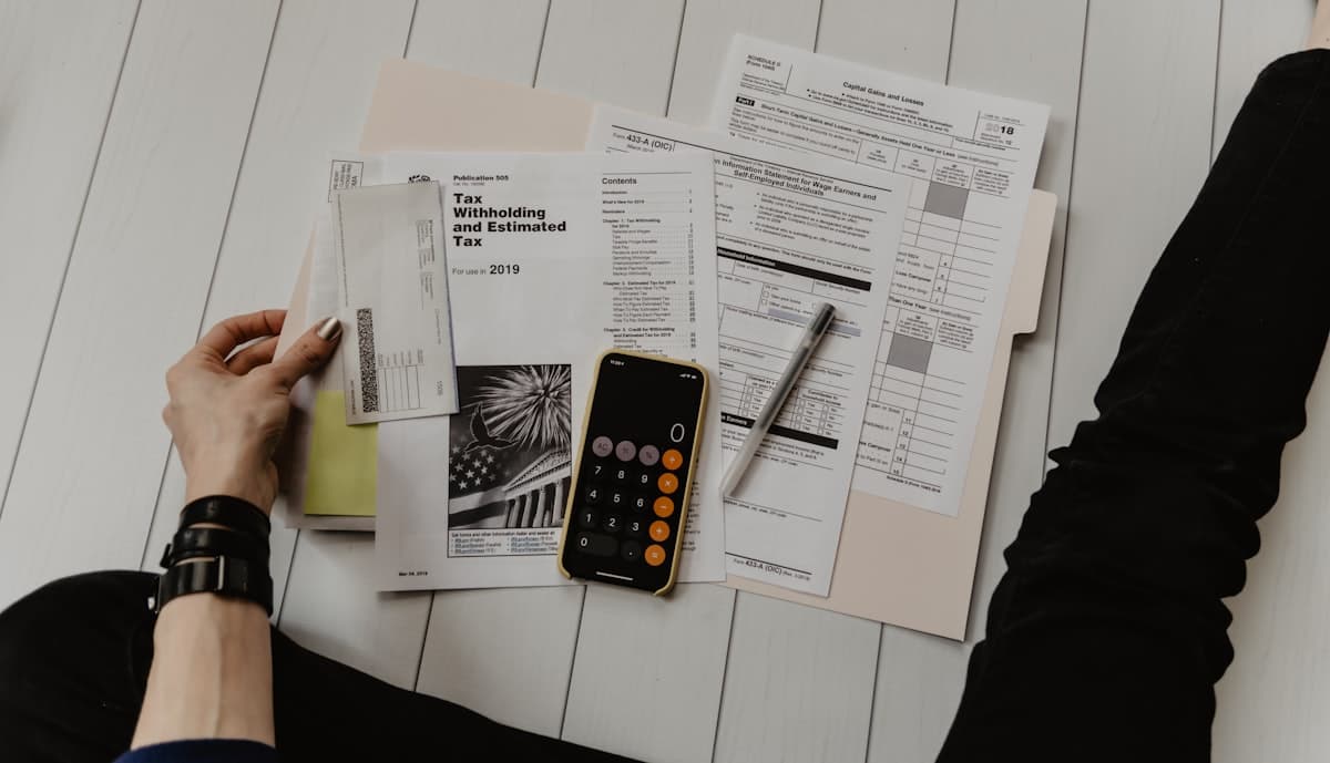 Tax forms, a calculator, and a pen laid out for review